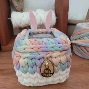 Cesto de crochê multicolor tons pastel, com orelhas de coelho em acrílico rosa e transparente, charm dourado Feliz Páscoa pendurado.